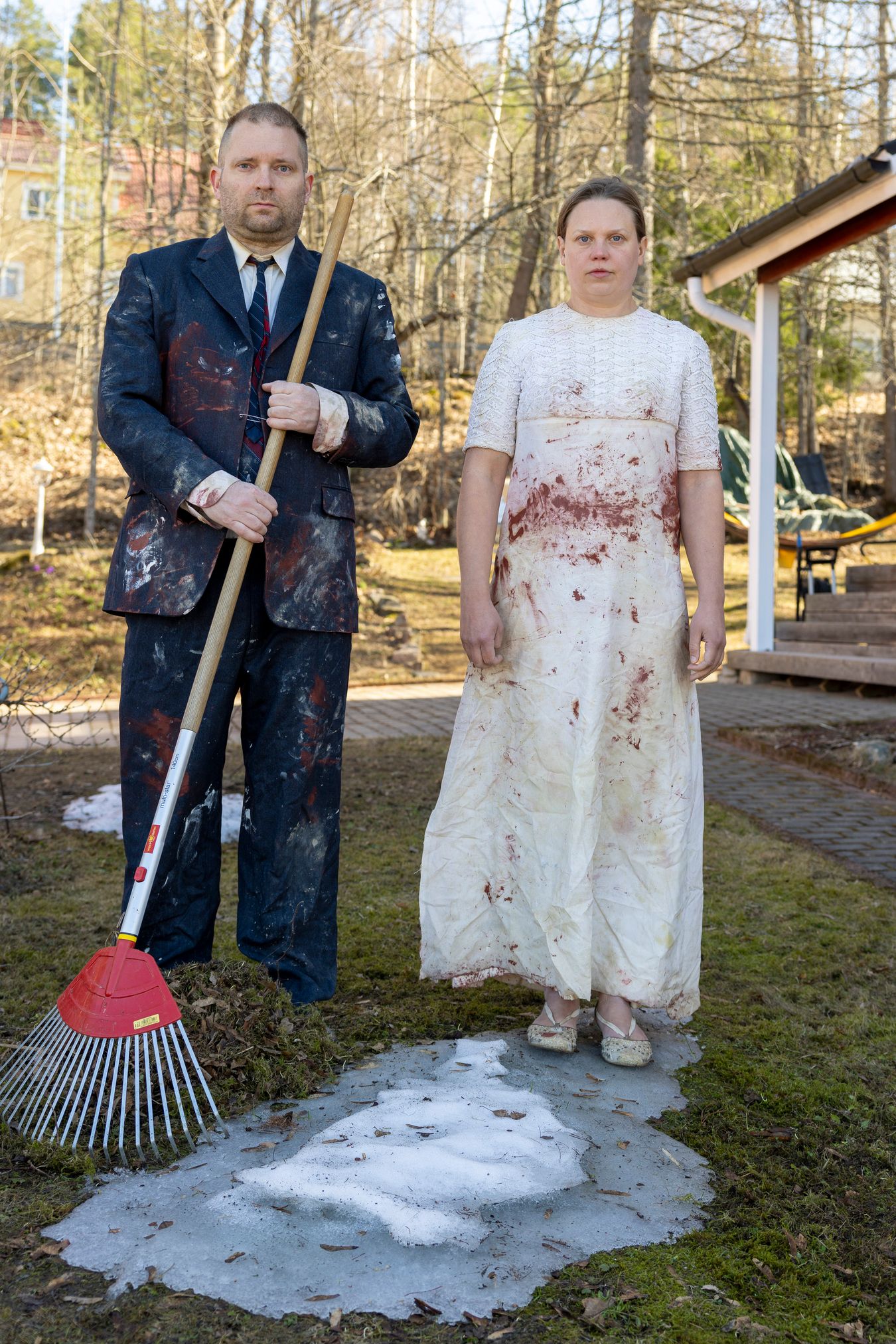 Mammu and Pasi standing in their wedding attire with neutral expressions staring at the camera.
