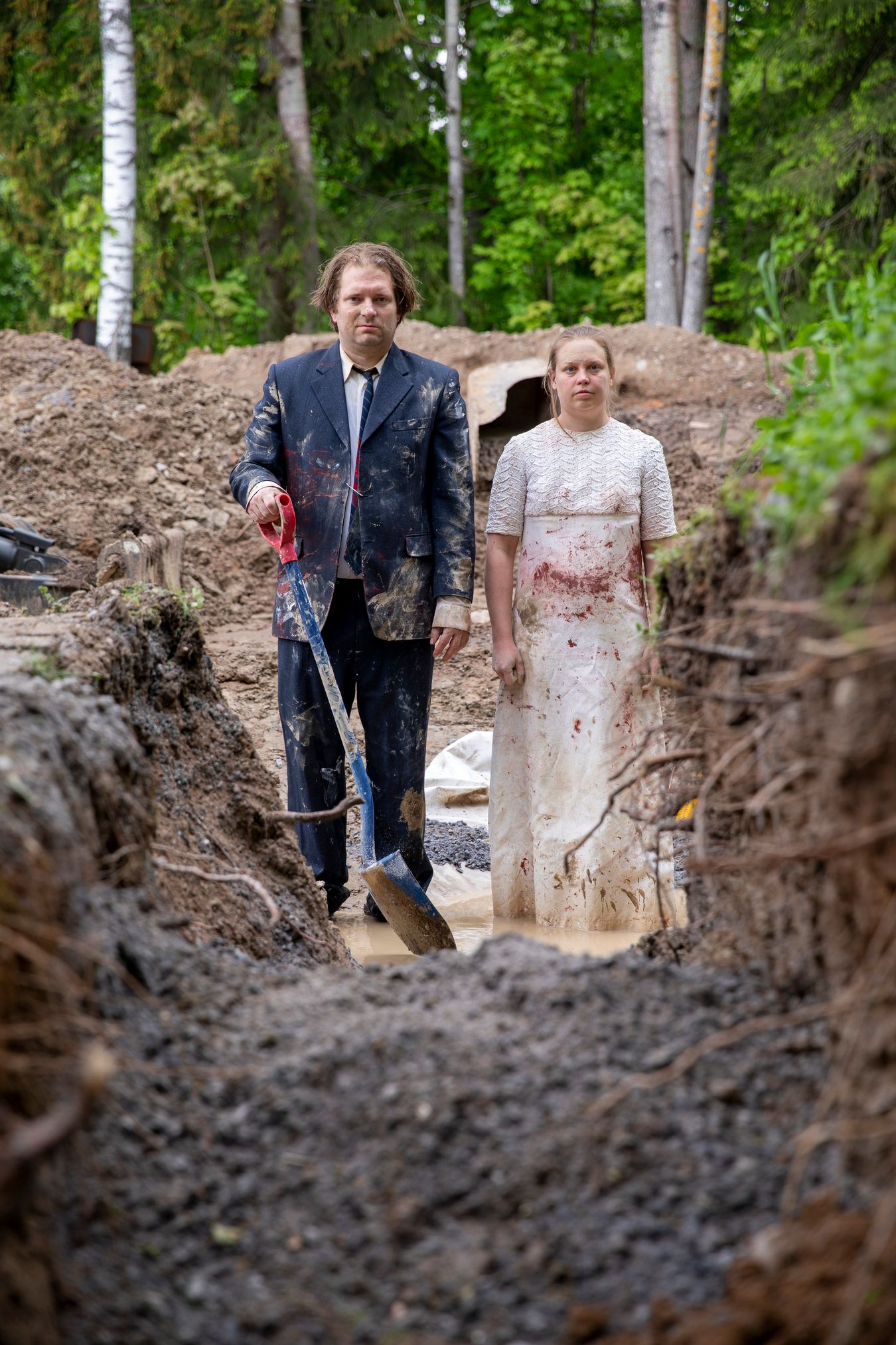 Mammu and Pasi standing in their wedding attire with neutral expressions staring at the camera.