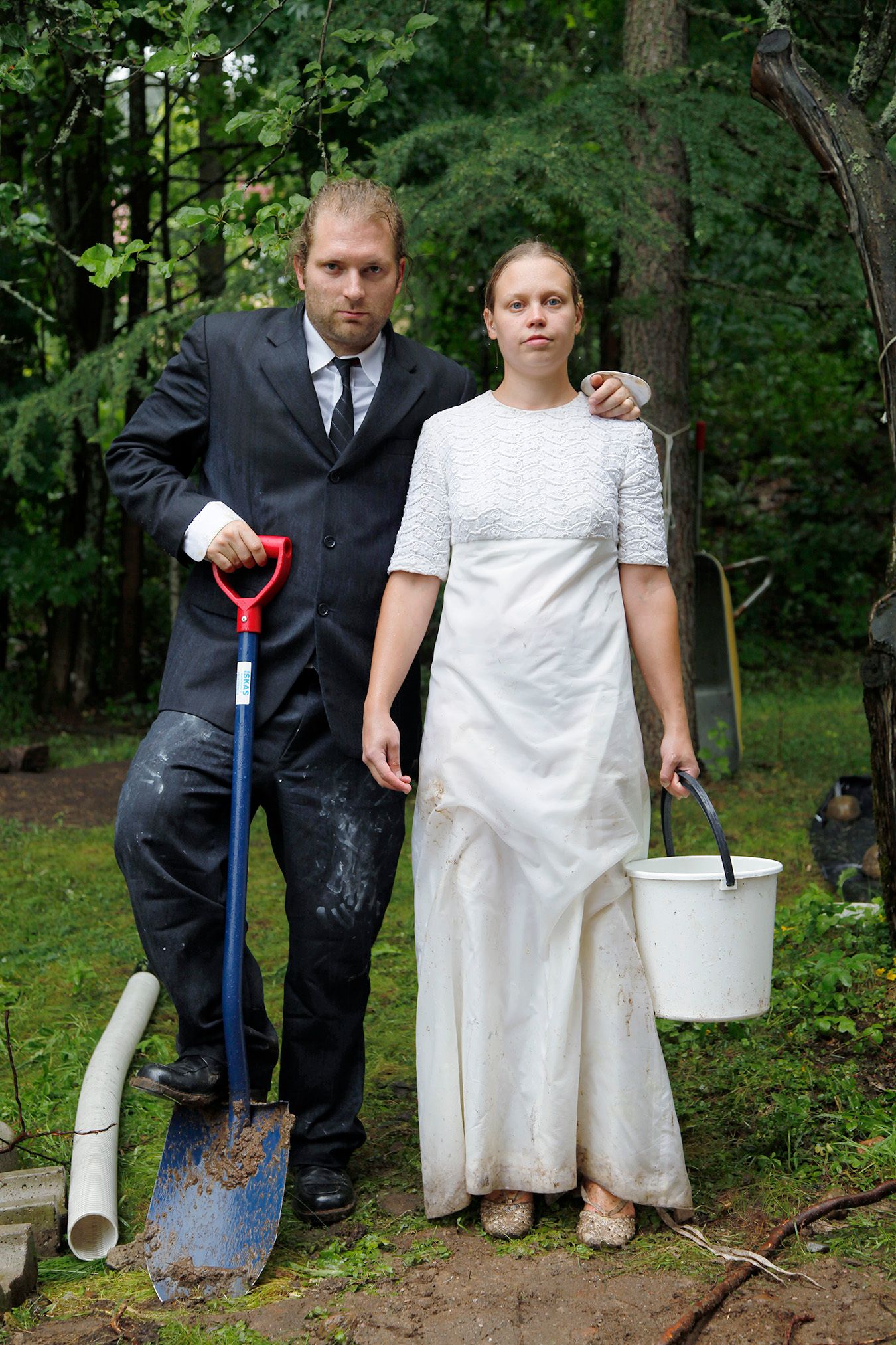 Mammu and Pasi standing in their wedding attire with neutral expressions staring at the camera.