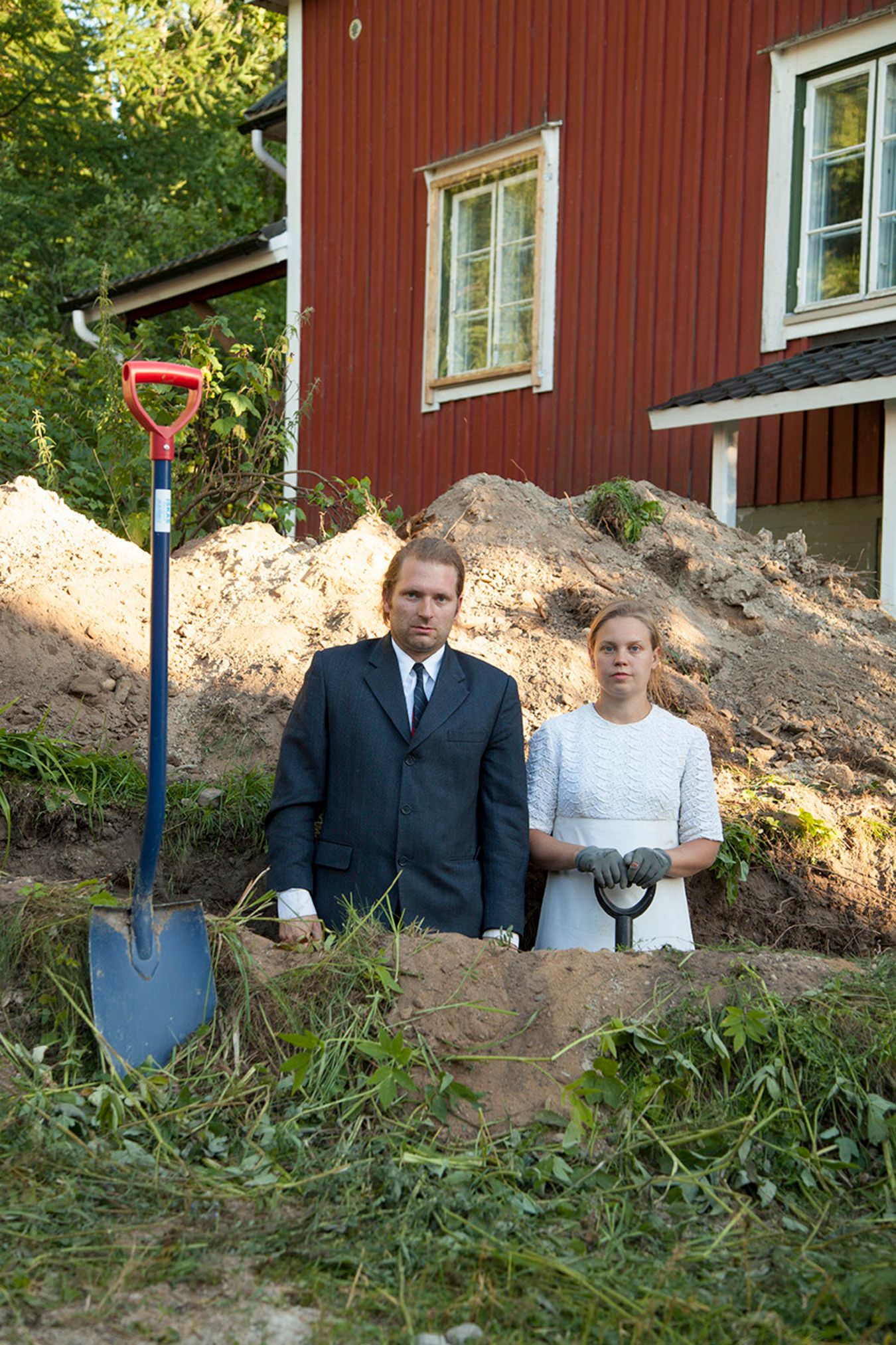 Mammu and Pasi standing in their wedding attire with neutral expressions staring at the camera.