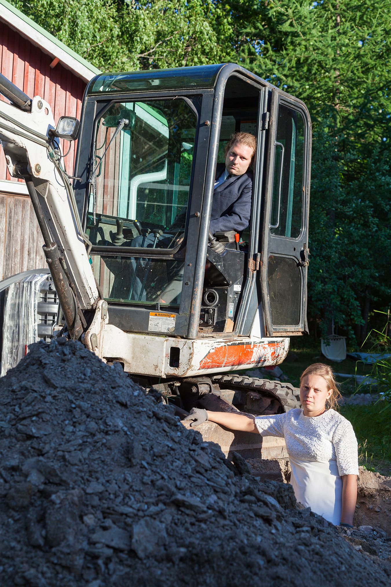 Mammu and Pasi standing in their wedding attire with neutral expressions staring at the camera.