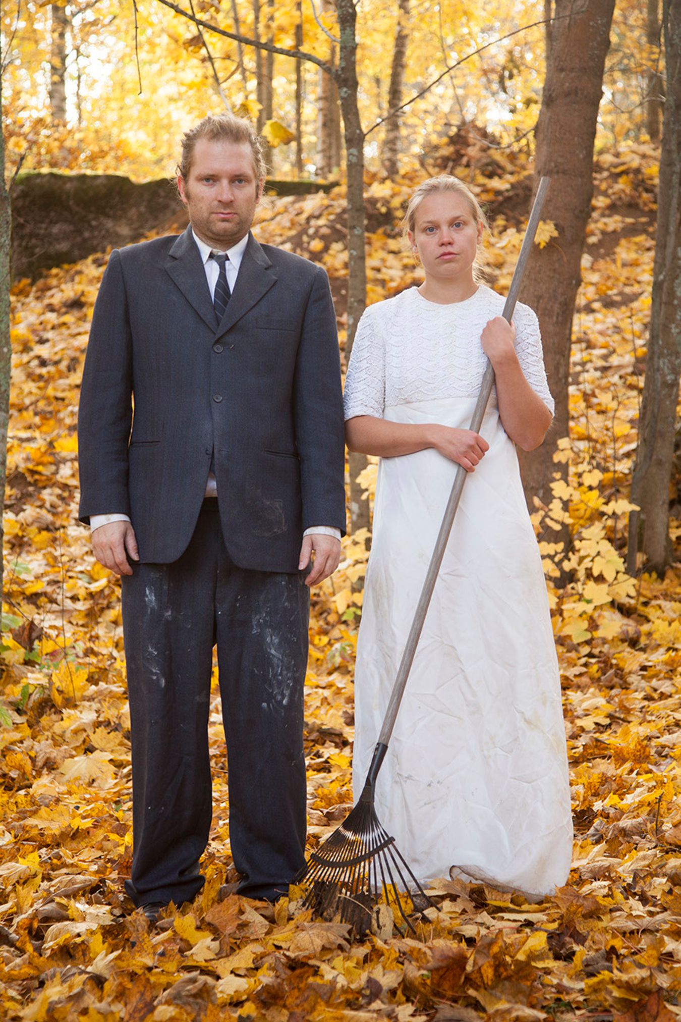 Mammu and Pasi standing in their wedding attire with neutral expressions staring at the camera.
