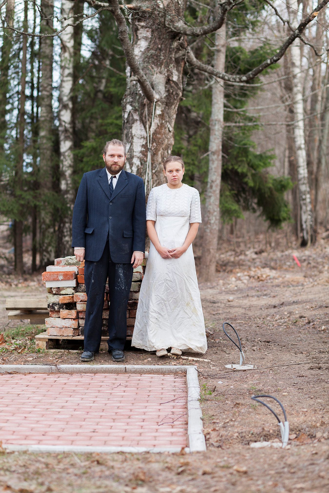 Mammu and Pasi standing in their wedding attire with neutral expressions staring at the camera.