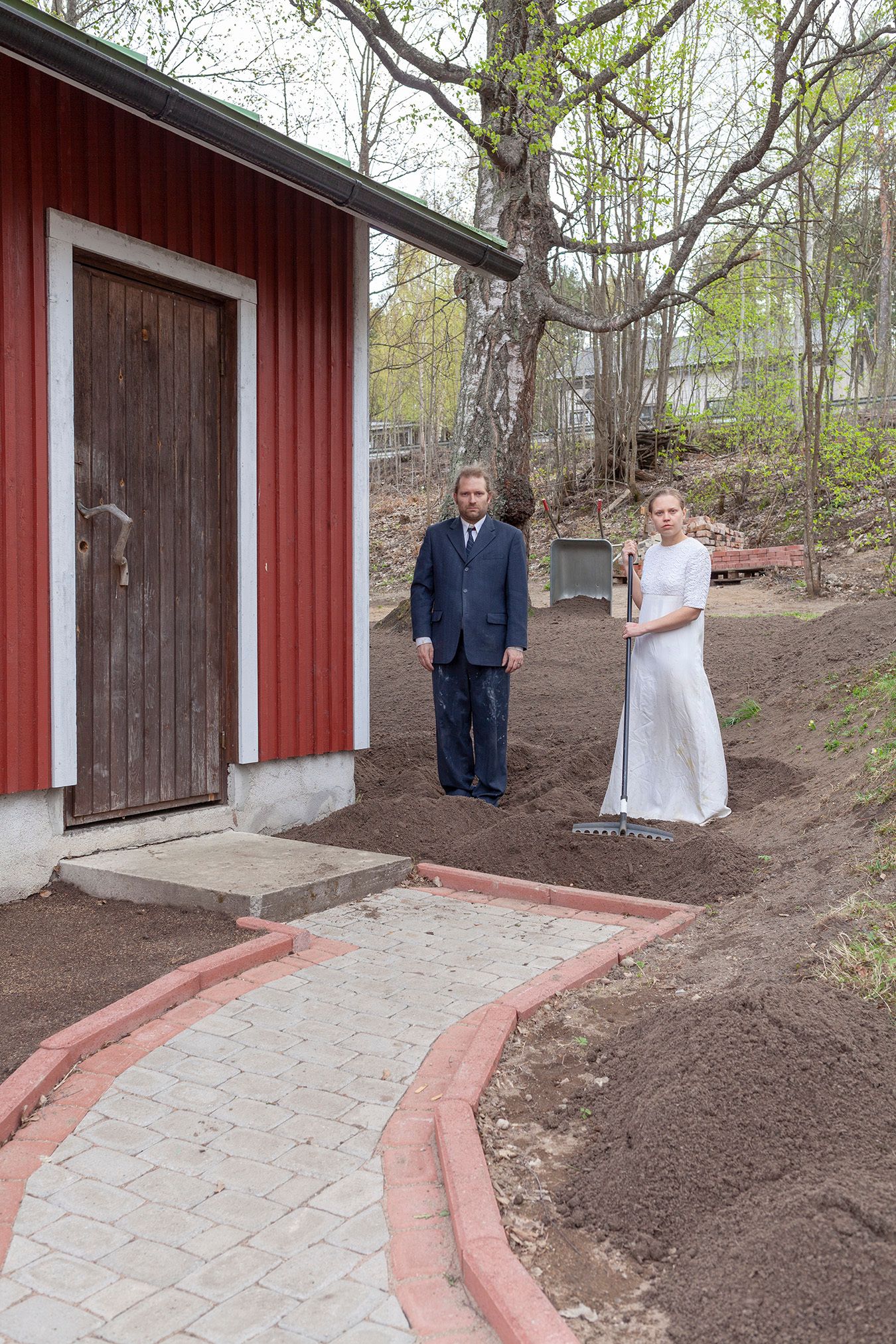 Mammu and Pasi standing in their wedding attire with neutral expressions staring at the camera.