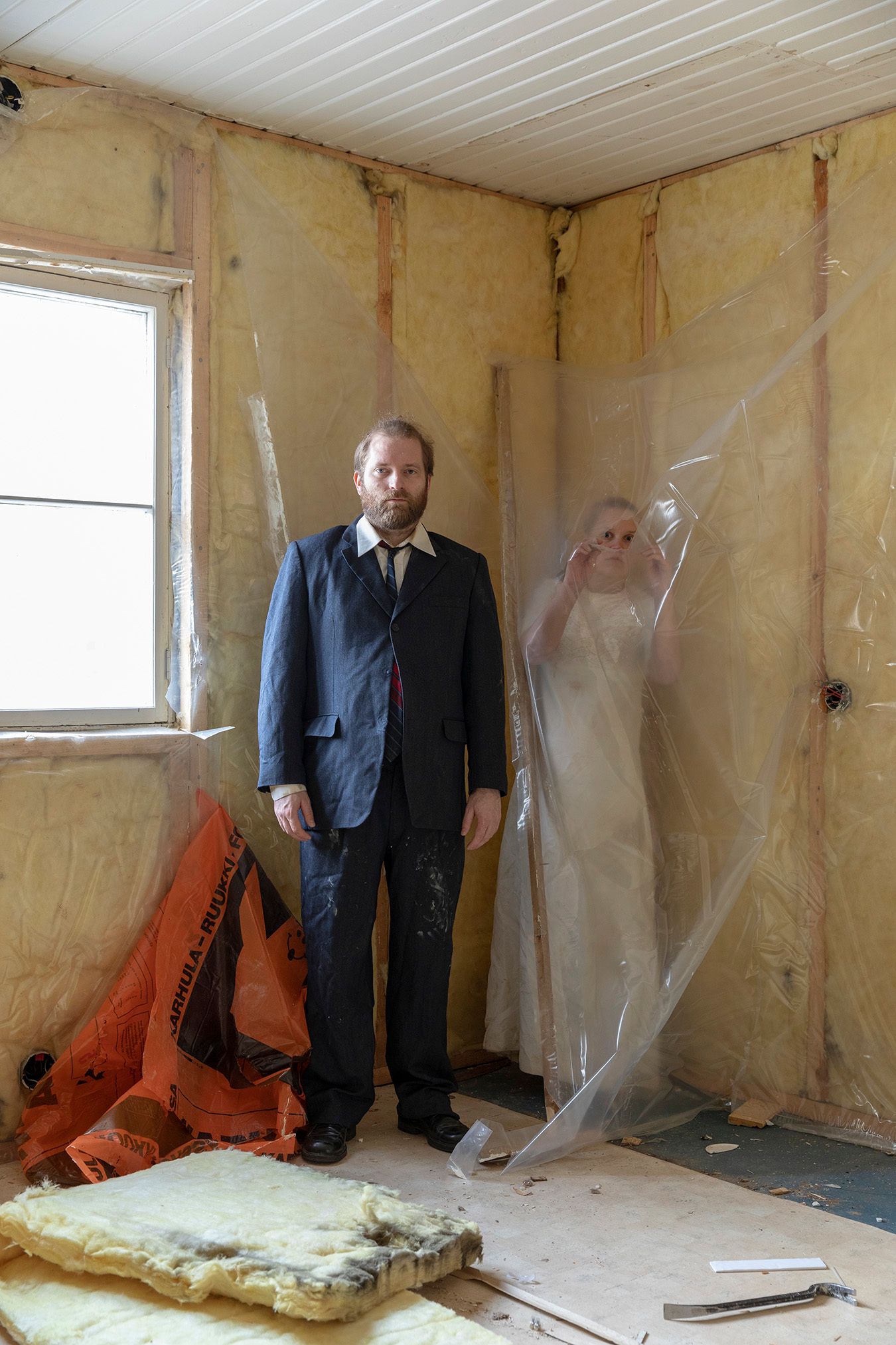 Mammu and Pasi standing in their wedding attire with neutral expressions staring at the camera.