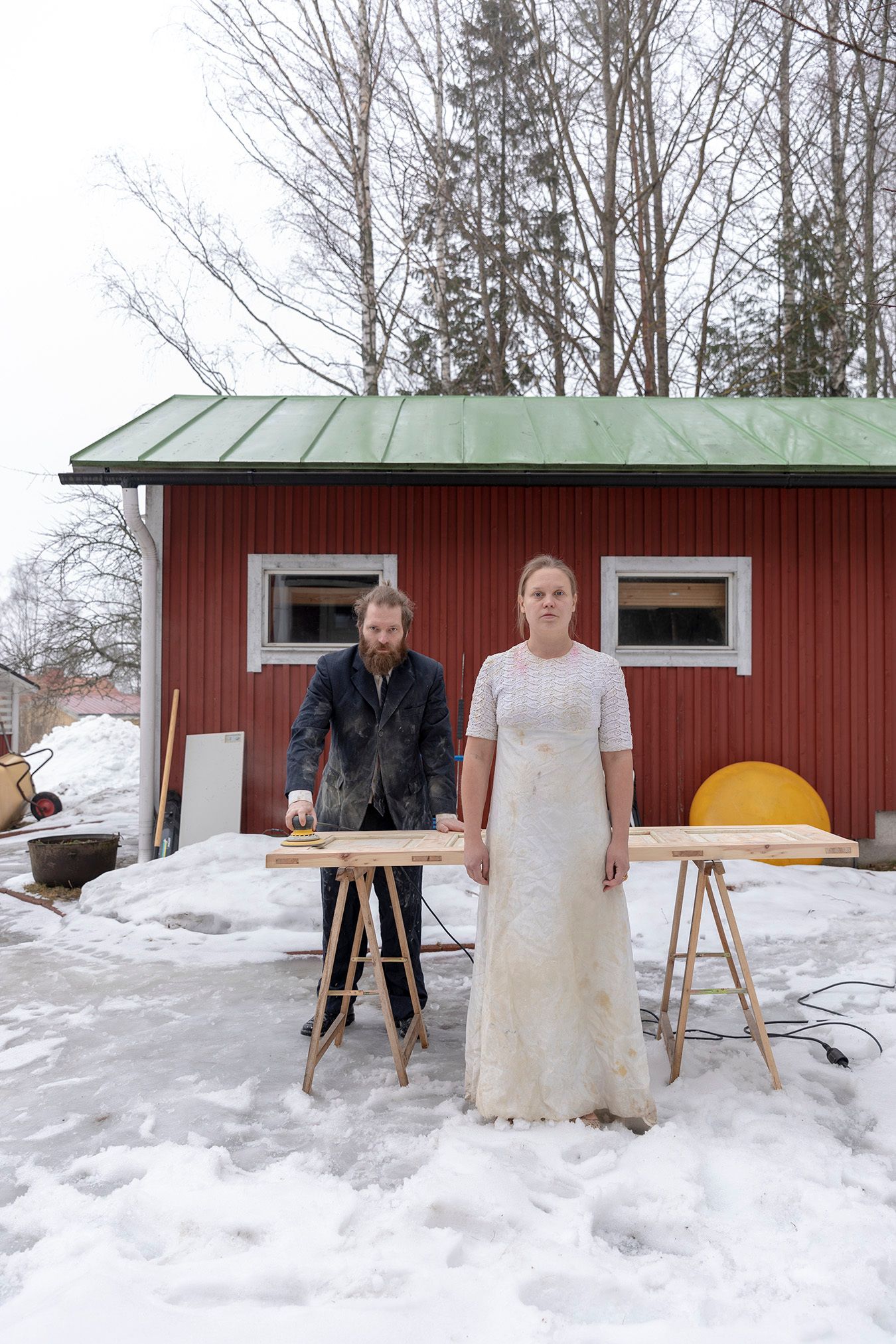 Mammu and Pasi standing in their wedding attire with neutral expressions staring at the camera.