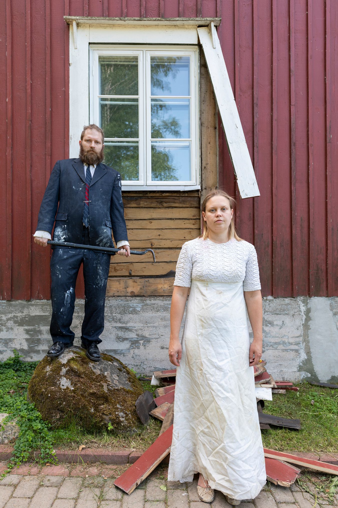 Mammu and Pasi standing in their wedding attire with neutral expressions staring at the camera.
