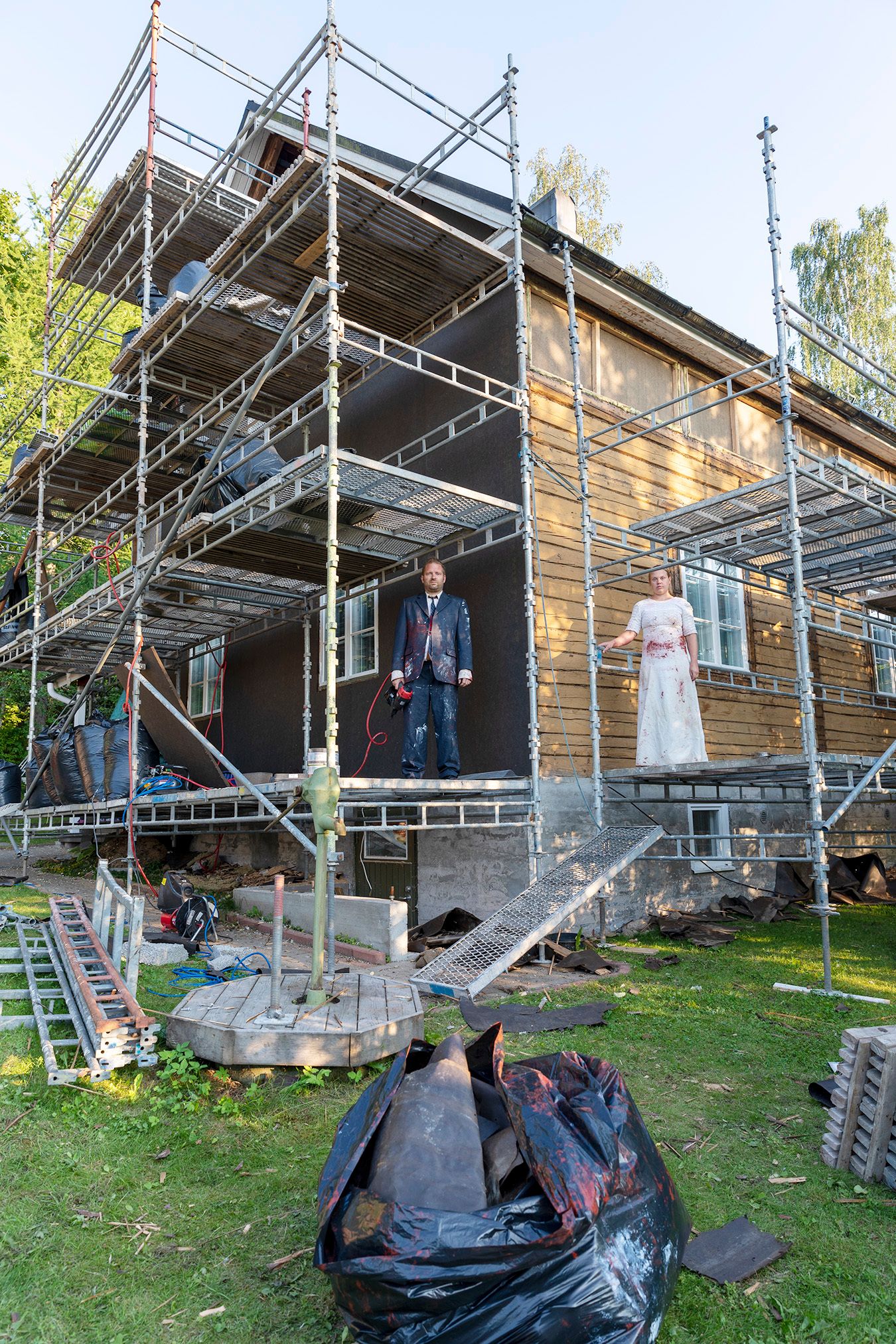 Mammu and Pasi standing in their wedding attire with neutral expressions staring at the camera.
