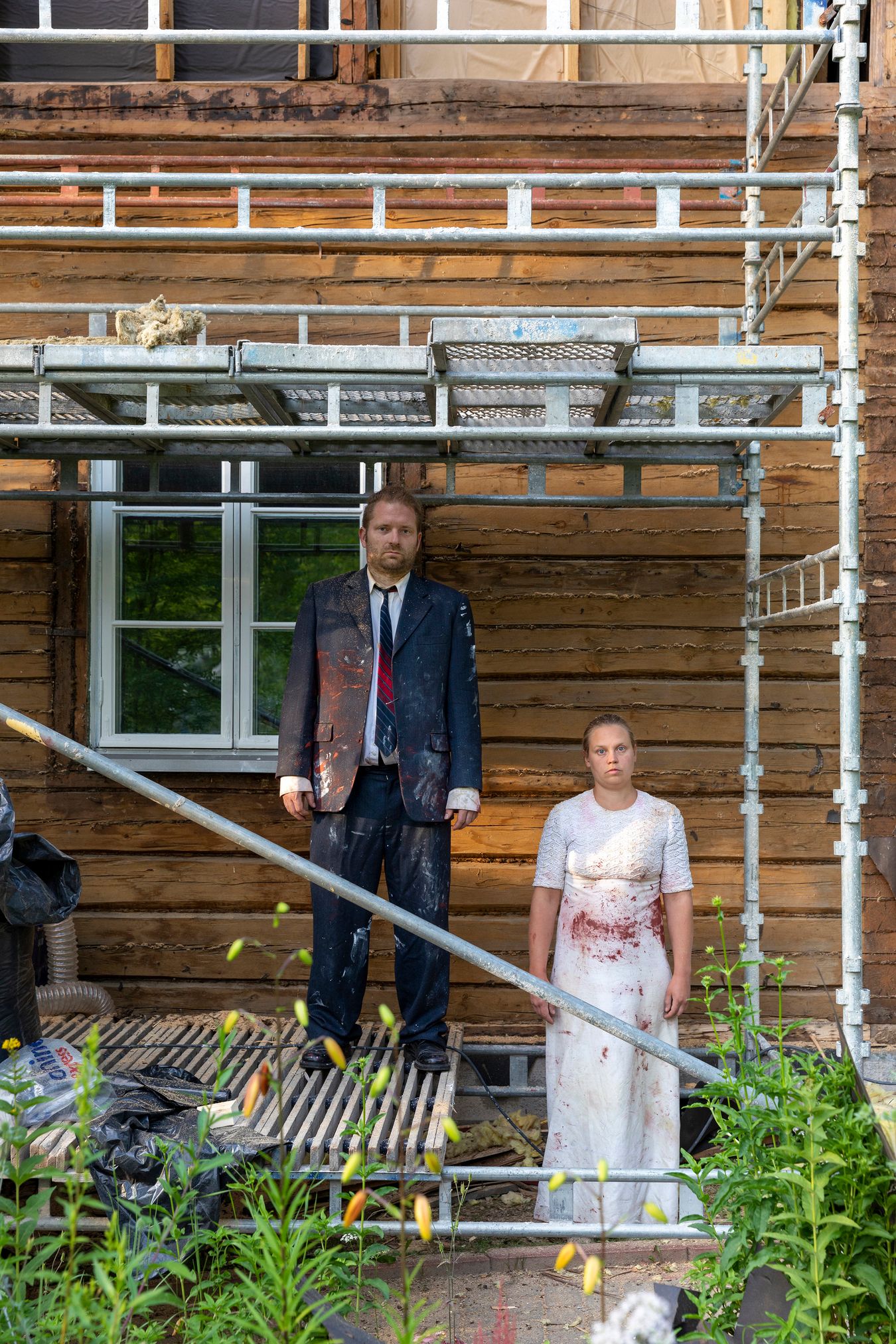 Mammu and Pasi standing in their wedding attire with neutral expressions staring at the camera.