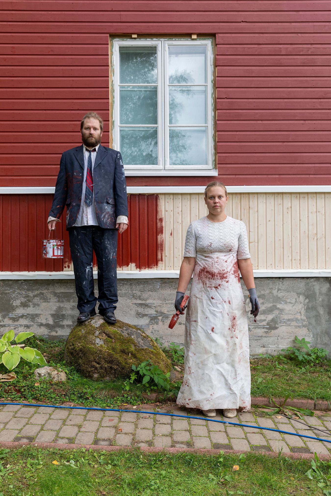 Mammu and Pasi standing in their wedding attire with neutral expressions staring at the camera.