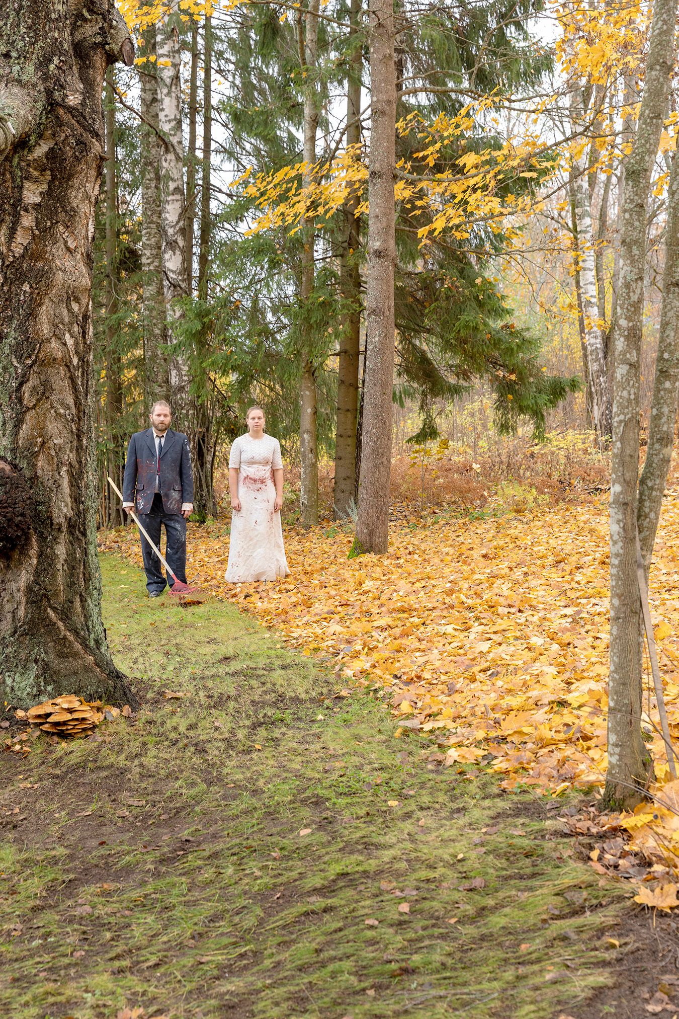 Mammu and Pasi standing in their wedding attire with neutral expressions staring at the camera.