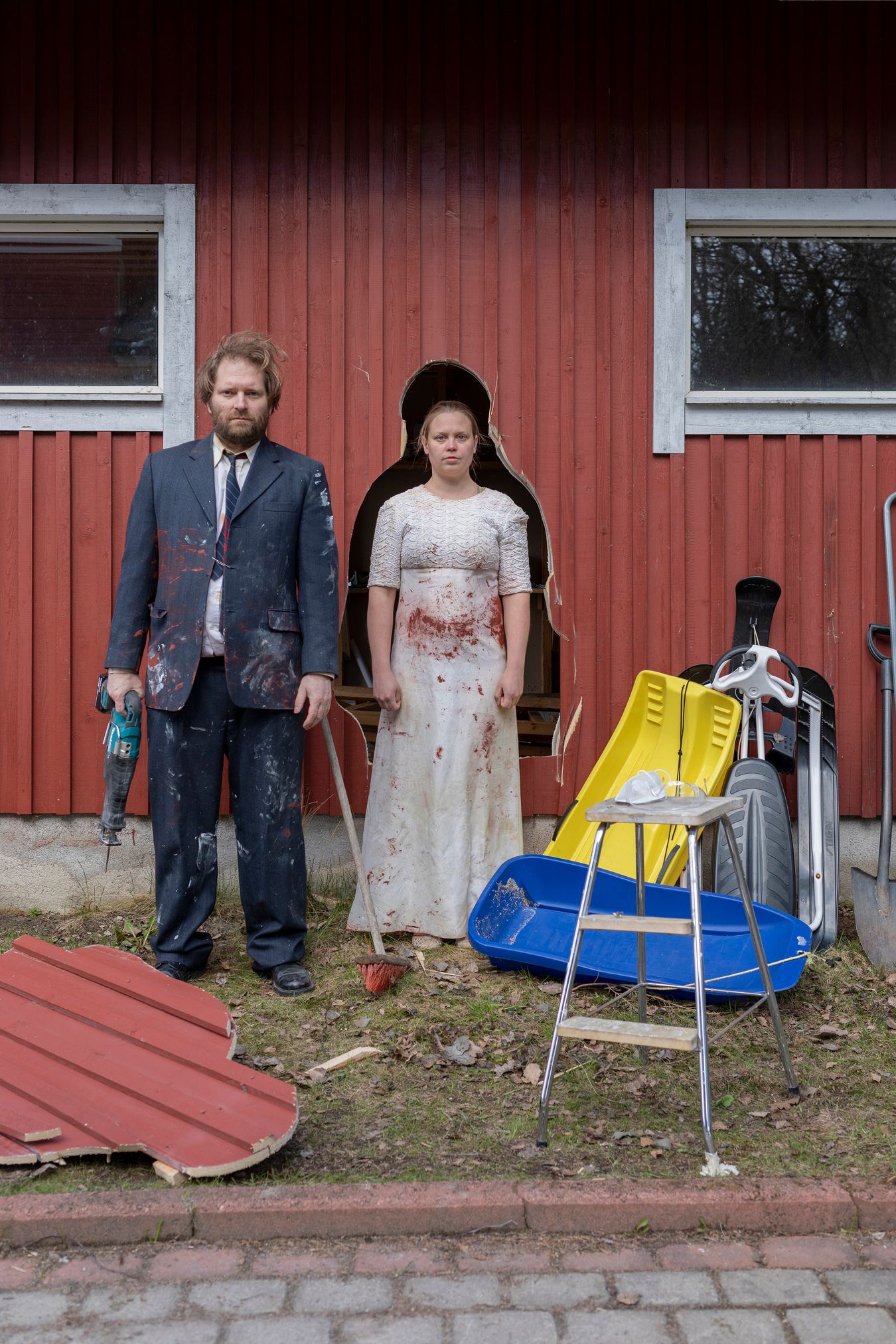 Mammu and Pasi standing in their wedding attire with neutral expressions staring at the camera.