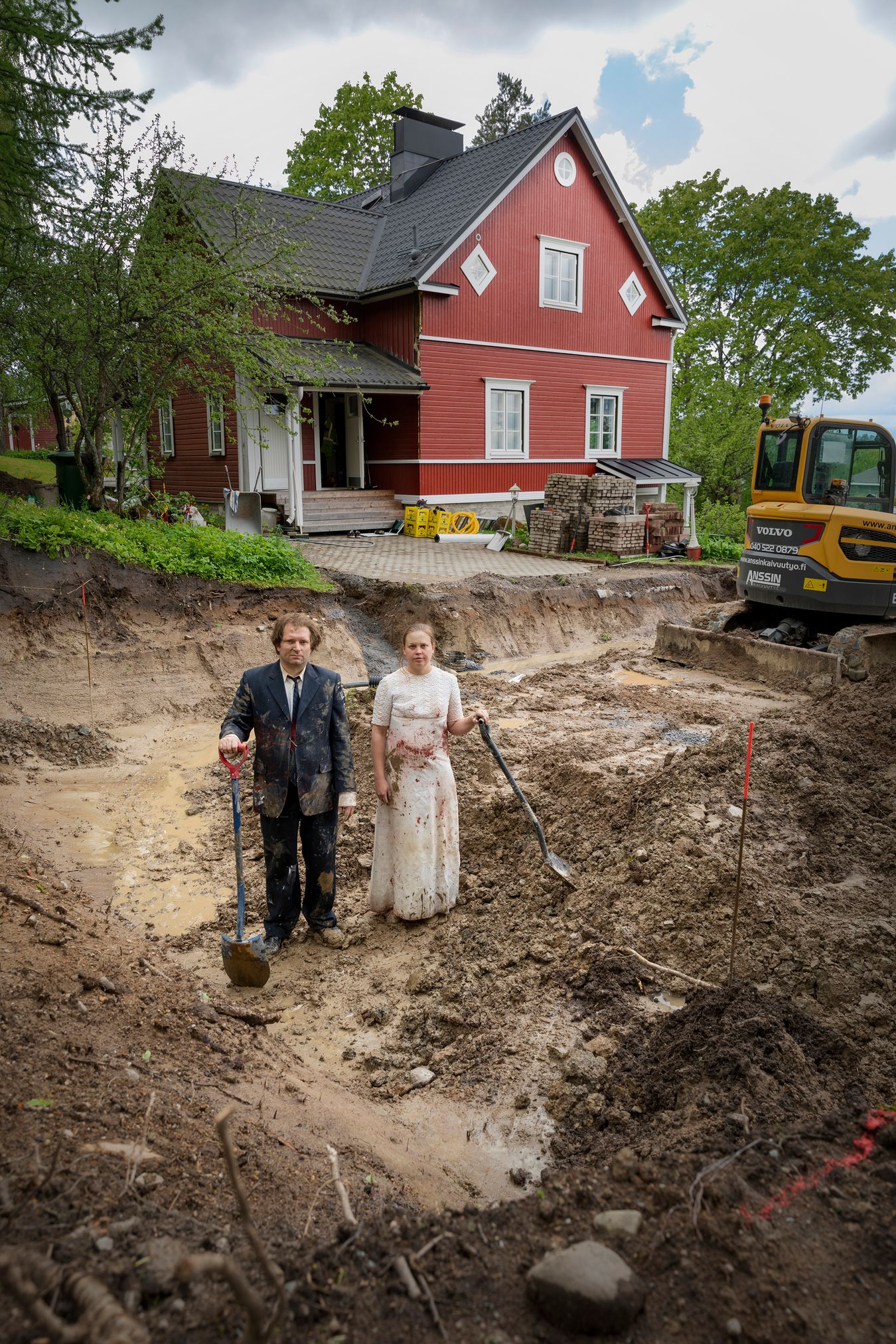 Mammu and Pasi standing in their wedding attire with neutral expressions staring at the camera.