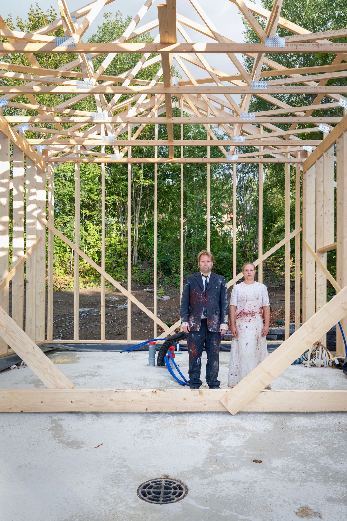 Mammu and Pasi standing in their wedding attire with neutral expressions staring at the camera.