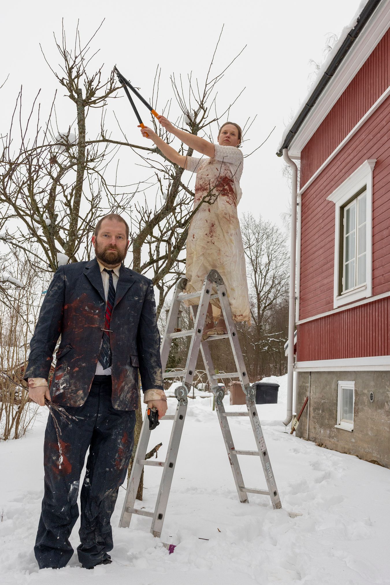 Mammu and Pasi standing in their wedding attire with neutral expressions staring at the camera.