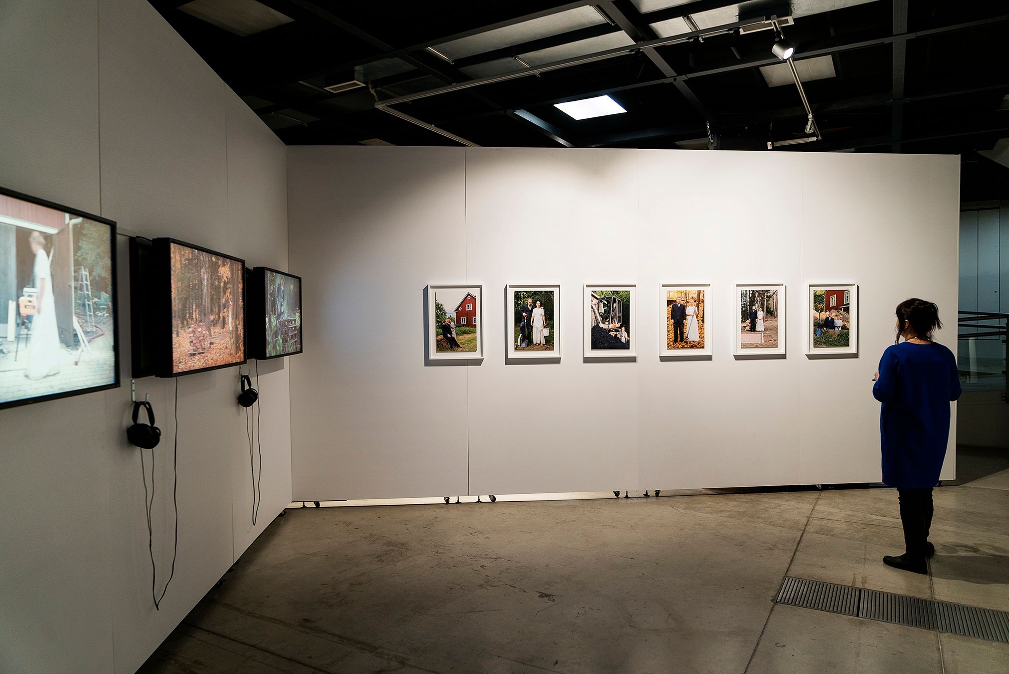 General view from an exhibition, showcasing Mammu's and Pasi's attire, some photographs, and some videos.