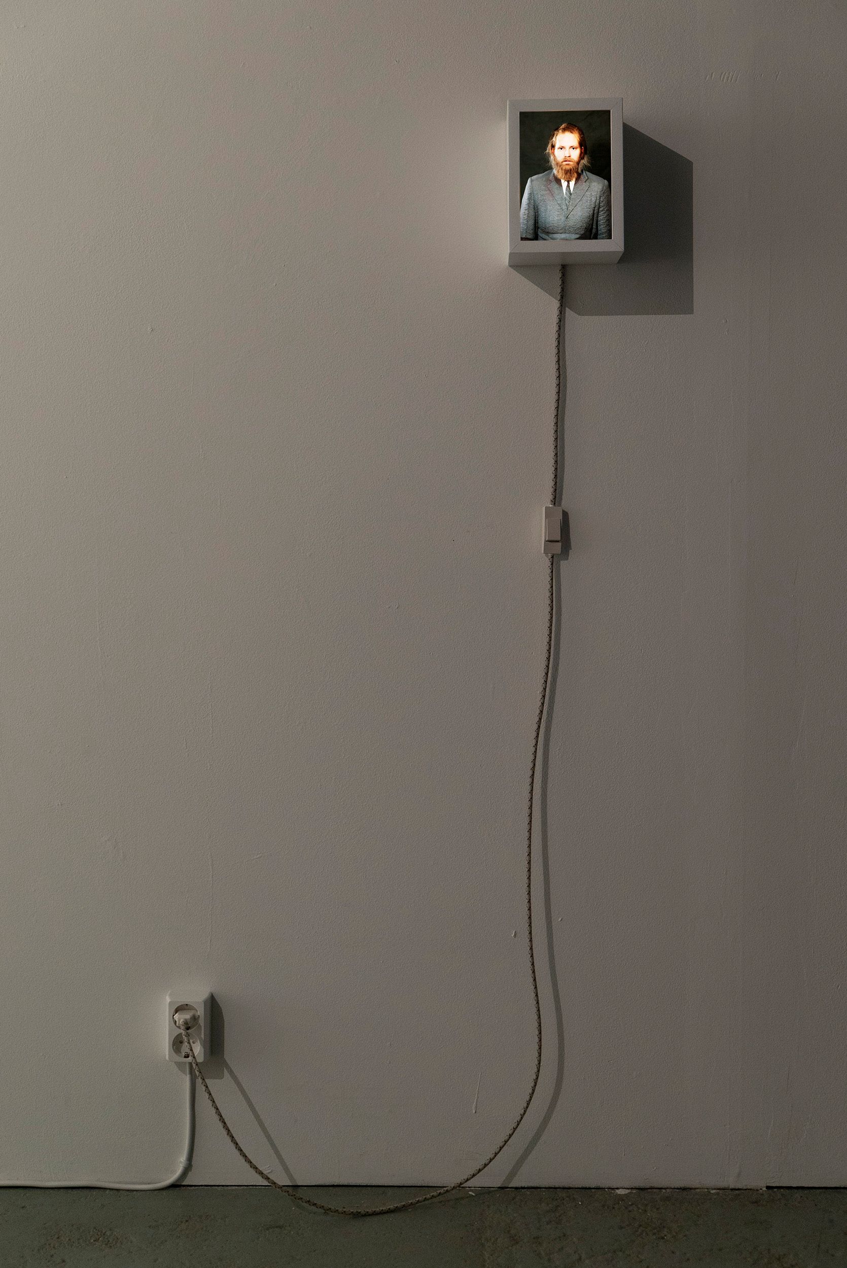 A photograph the fusion-picture of Mammu and Pasi being displayed in a small lightbox on a wall.