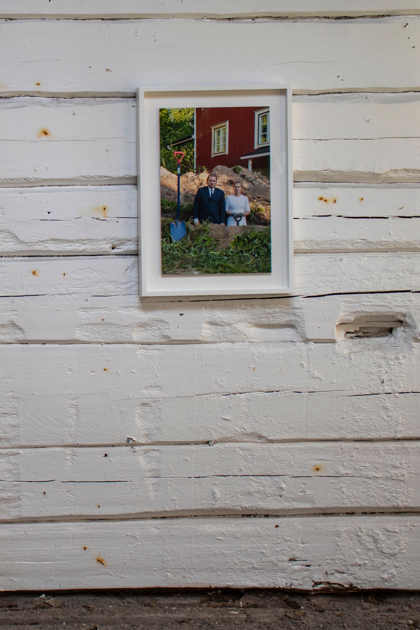 Close-up picture of a photograph of Mammu and Pasi hanging on a white wooden wall.