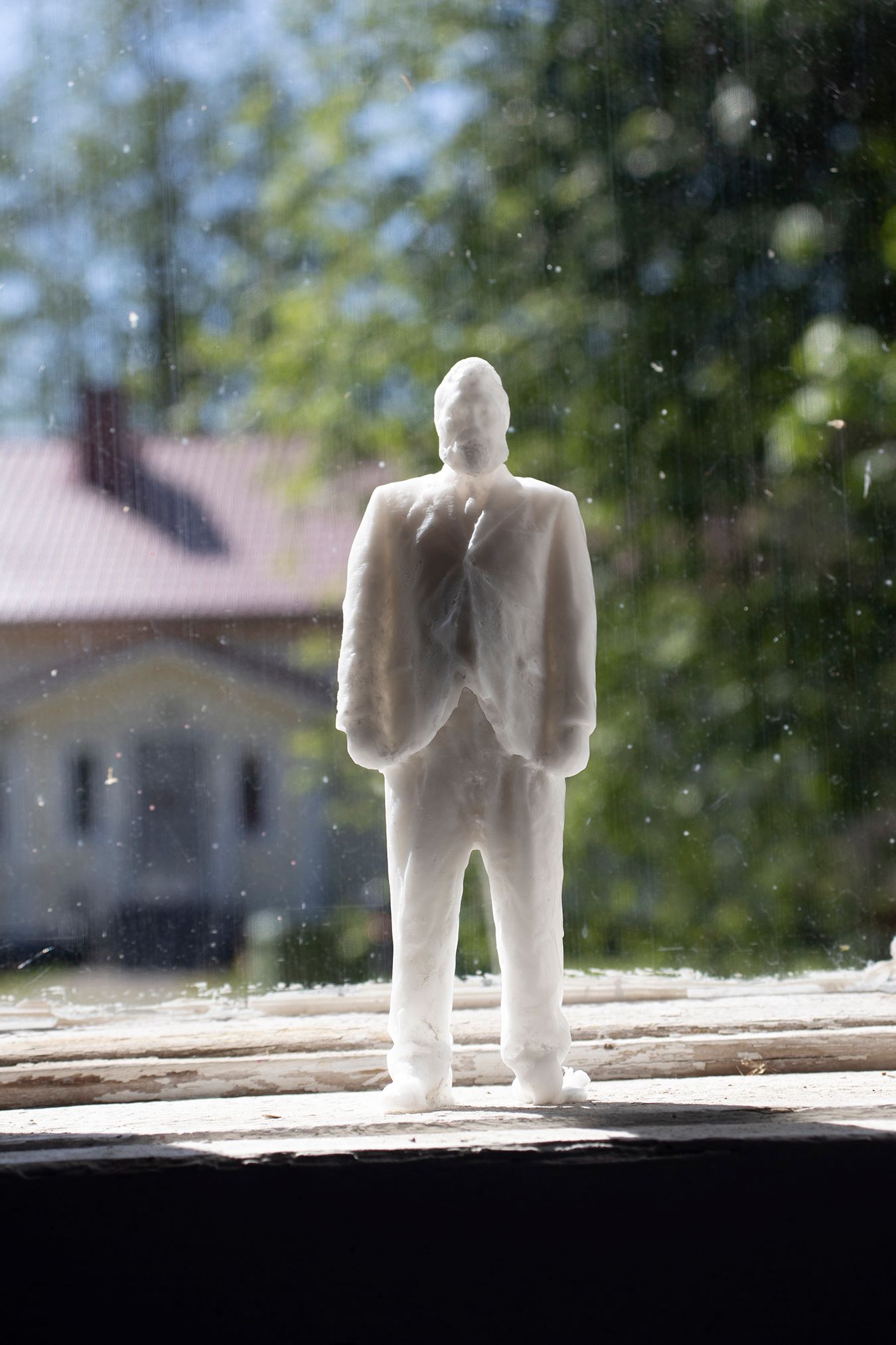 A close-up picture if a white candlewax figure of Pasi standing on the windowsill, waiting to melt.