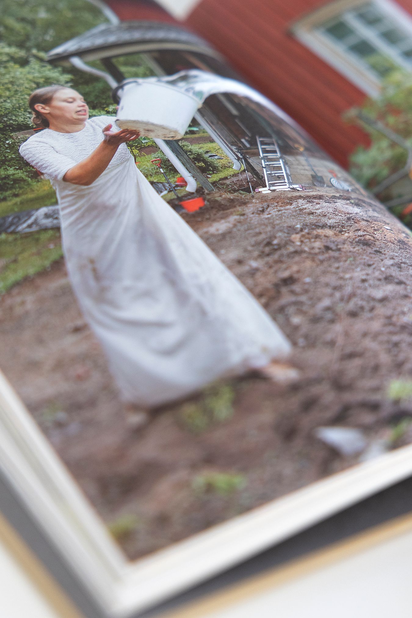 Close up of a page from the book with a photograph of Mammu throwing water with a bucket.