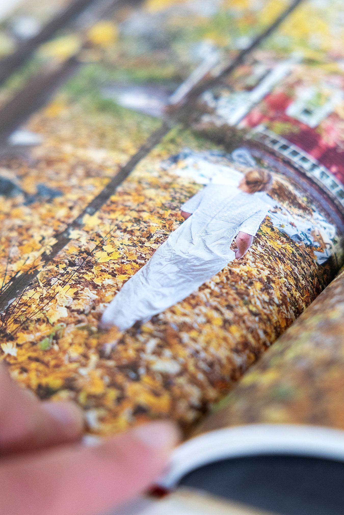 Close up of a page from the book with a photograph of Mammu turned away from the camera in the middle of some autumn leaves.
